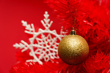 Christmas ornament hangs from a red tree with a white snowflake on a red background