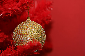 Gold ornament hanging from a red Christmas tree decoration