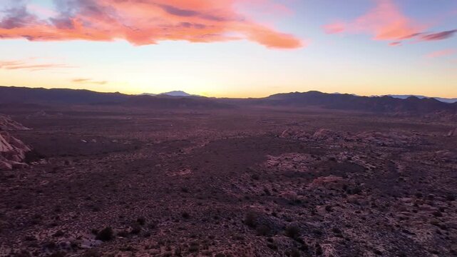 Crimson sunset illuminates valley and rock formations viewed from Ryan Mountain Trail in Joshua Tree National Park California