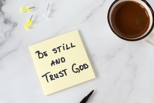 Be still and trust God, inspirational handwritten quote with coffee cup. Top view. Christian biblical concept of patience, peace, and faith in Jesus Christ.