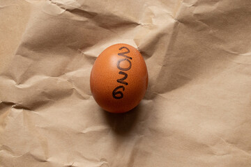 A brown chicken egg with the inscription 2026 lies on crumpled craft paper, a symbol of the New Year, time