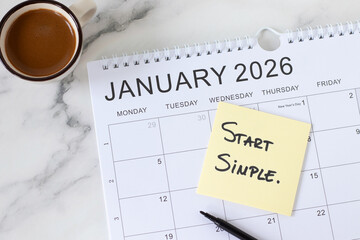 Start simple, inspirational handwritten quote with 2026 calendar and coffee cup. Top view. New beginning, success, and business goals concept.