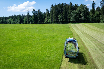 Landwirt in Bayern m&auml;ht Gras und erntet es in einem Arbeitsgang mit einem Ladewagen, Luftbild.