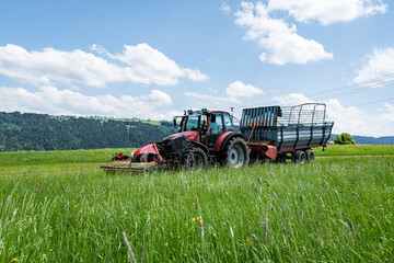 Gr&uuml;nfutterernte im Allg&auml;u, Traktor mit vorgebautem M&auml;hwerk und Ladewagen bei der Grasernte.
