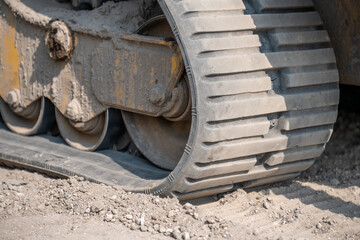 Heavy machinery tracks on construction site showing detail of rubber tread and gravel during daytime work hours