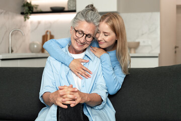 Obraz premium Elderly mother and adult daughter share a joyful moment in their cozy apartment