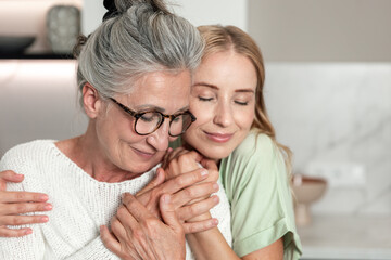 Elderly mother and adult daughter share a joyful moment in their home together