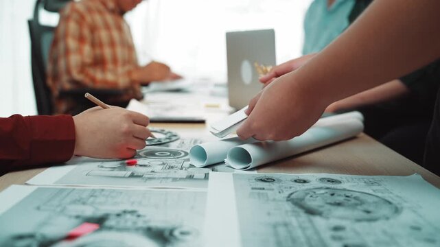 Hands of professionals engage in a collaborative project discussion while reviewing design documents in a modern office setting, showcasing teamwork and creativity. SACTR