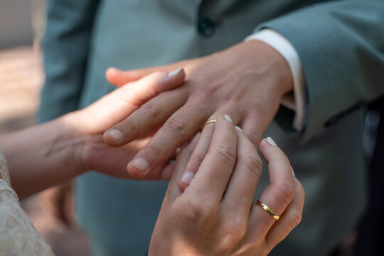 H&auml;nde eines Brautpaar beim Anstecken des Ehering nach der Ring&uuml;bergabe auch Ringtausch w&auml;hrend der Trauung im Rahmen einer Hochzeit im Standesamt
