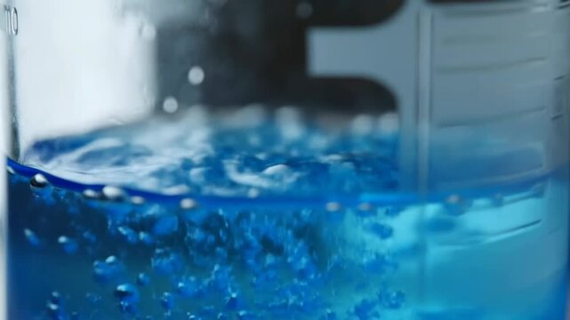 Bubbling blue liquid reaction in scientific glassware with dynamic patterns