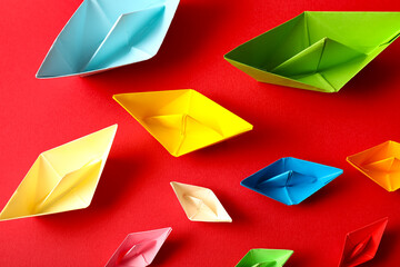Colorful paper boats on red background