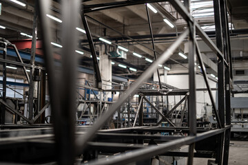 Industrial vehicle manufacturing workshop with metal bus frames and body structures under assembly....