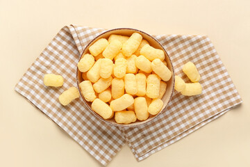 Bowl with sweet corn sticks on beige background