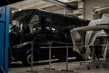 Fototapeta premium Industrial vehicle manufacturing workshop with metal bus frames and body structures under assembly. Large factory interior shows fabrication, welding, and custom vehicle production in progress.