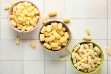 Bowls with sweet corn sticks on white tile background