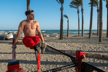 Fototapeta premium Man doing l sit calisthenics workout on beach bars