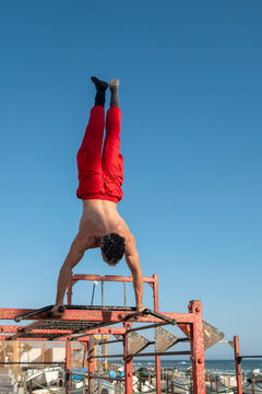 Man performing handstand on outdoor parallel bars