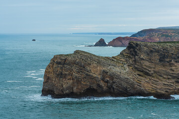 Massive rock formations rise from the Atlantic near the dramatic coast of Sagres in Portugal.