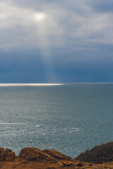 Sunlight pierces the clouds and illuminates the sea below.