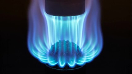 A blue flame burns brightly from a burner on a dark background