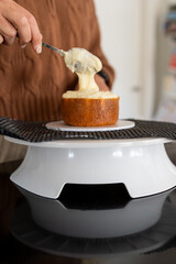 A women's hands spooning icing onto a cake