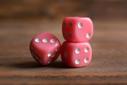 Pink game dices on wooden background