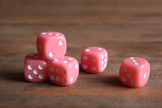 Pink game dices on wooden background