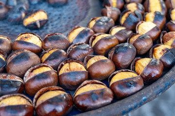 Traditional vintage French equipment for roasting and grilling fresh chestnuts over open fire, delicious street food, eating nuts on streets of Paris in autumn