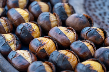 Traditional vintage French equipment for roasting and grilling fresh chestnuts over open fire, delicious street food, eating nuts on streets of Paris in autumn