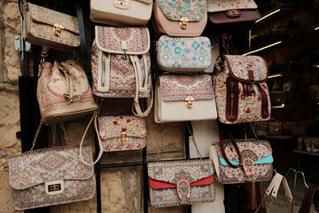 Colorful patterned handbags displayed on a market wall, featuring traditional textile designs and decorative details. Street souvenir stall with handmade accessories and rich cultural style.