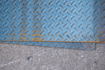 Imagen cenital de varias placas de metal color azul oxidadas en el suelo tipo textura