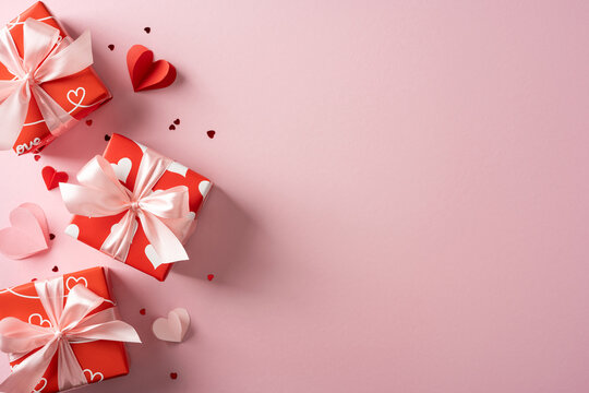 Red gift boxes tied with pale pink ribbons lie on a pastel pink backdrop, evoking Valentine&rsquo;s Day warmth and romance. Perfect for gifts, greetings, and festive celebrations