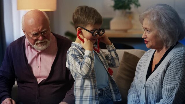 Grandson playing doctor and patient with grandparents, fun family roleplay
