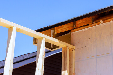 Workers fix roof structure of building with wooden beams.