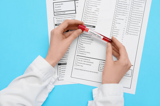 Female doctor's hands with blood sample of cortisol and laboratory test forms on blue background. Medical concept