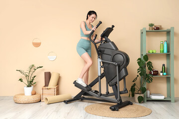 Sporty young woman training on modern exercising bike in stylish gym