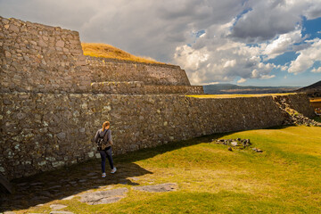 Tourist woman walking past ancient Tlaloc temple pyramid ruins in Calixtlahuaca, Mexico
