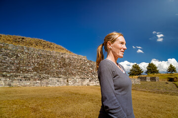 Tourist woman looking at horizon with ancient Tlaloc temple behind in Calixtlahuaca, Mexico