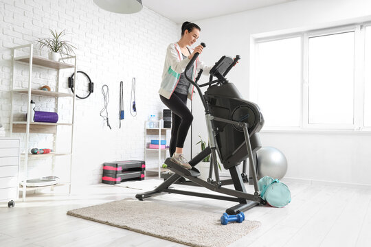 Sporty young woman training on modern exercising bike in light gym - Powered by Adobe