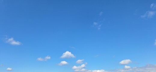 Beautiful bright blue sky with white fluffy clouds on sunny day