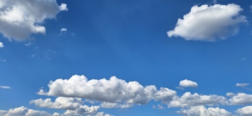 Beautiful bright blue sky with white fluffy clouds on sunny day