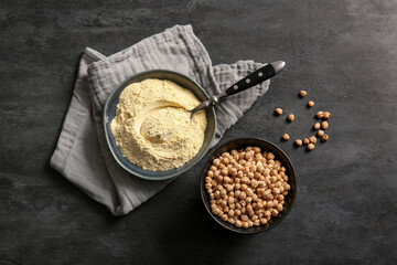 Bowls with chickpea flour and beans on black background