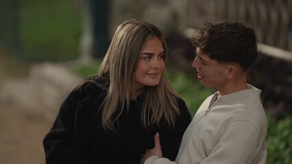 A young couple in Paris France share a romantic moment outdoors looking at each other with love and...