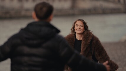 A romantic couple reunites in Paris France with a woman in a fur coat smiling at her partner The image captures love and affection in an urban setting suitable for travel and relationship themes.