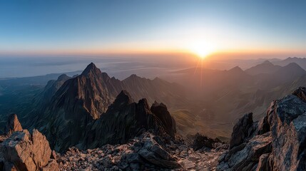Panoramic View of Jagged Mountain Peaks at Sunrise with Warm Golden Light and Blue Sky Casting Shadows Over the Rocky Landscape