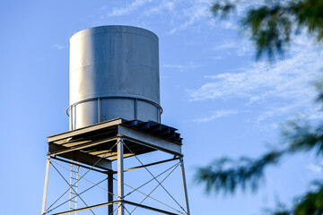 An elevated water storage tank supported by a steel tower against a clear sky, illustrating municipal water infrastructure, utility storage systems, and public service operations