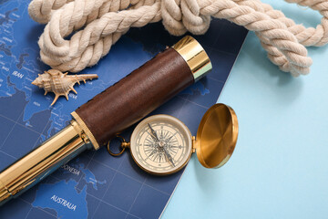 Composition with golden vintage compass, spyglass and world map on blue background