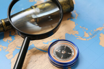 Modern compass, spyglass and magnifier on map as background, closeup