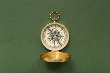 Golden compass on green background, closeup