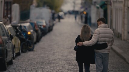 A romantic couple walks arm in arm down a cobblestone street in Paris France The image showcases...